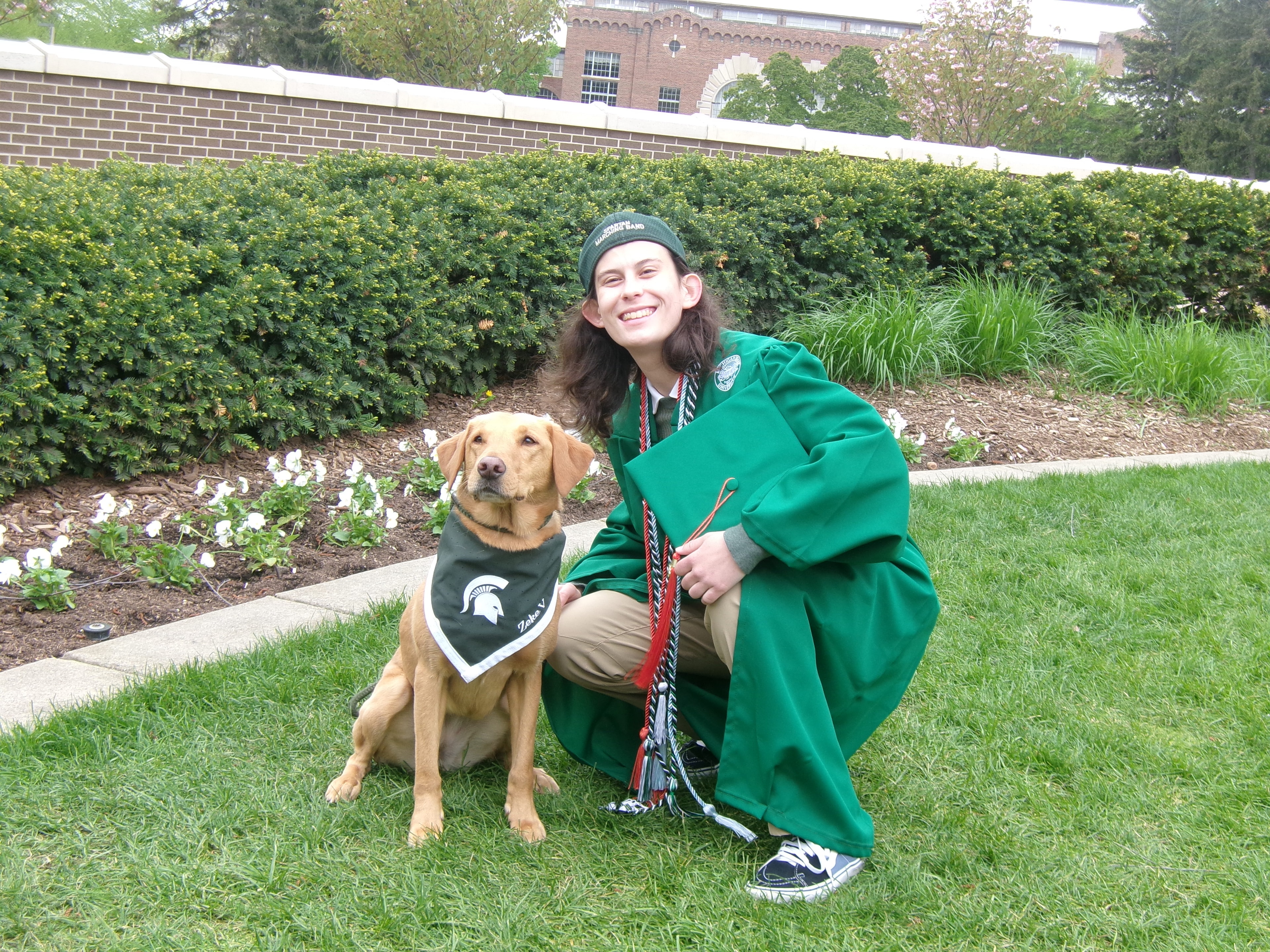 MSU graduate with Zeke the WonderDog on campus lawn
