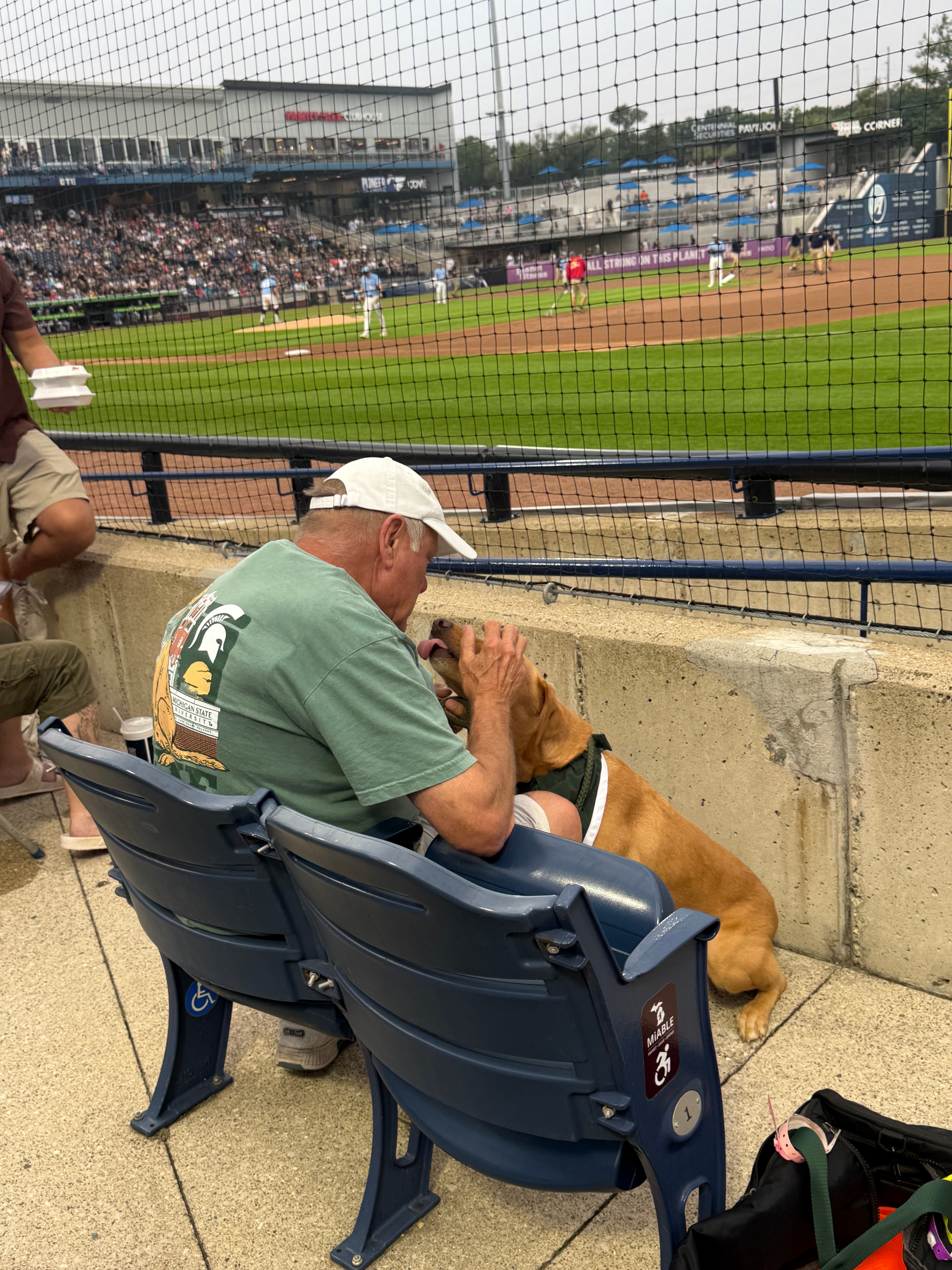 Zeke getting pets from a fan in the stadium seats
